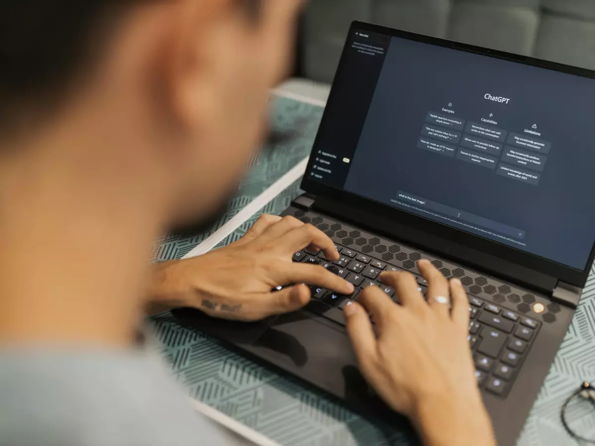 A person working on a laptop, with their hands on the keyboard and the screen visible in the background.