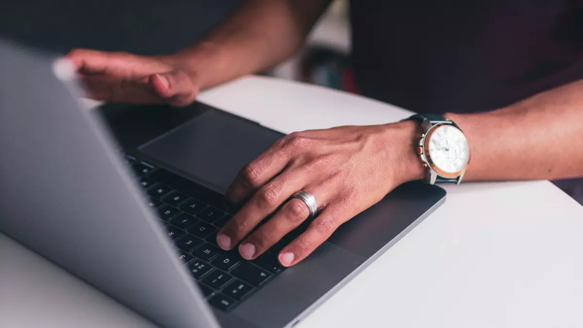 A person is coding on a laptop, looking at the screen.