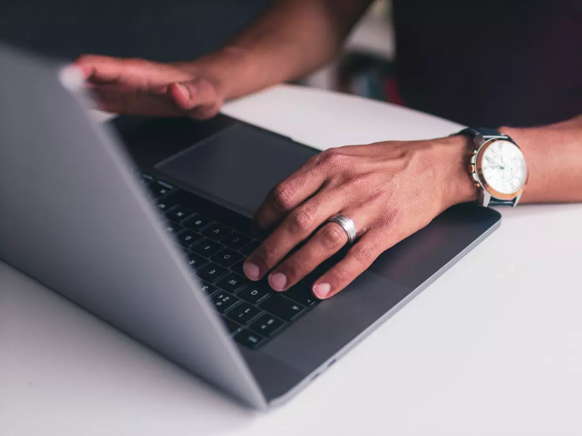 A person is coding on a laptop, looking at the screen.