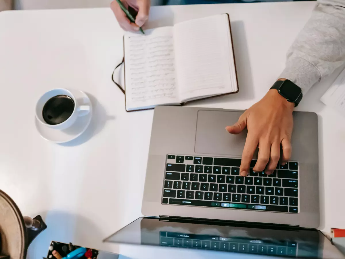 A person wearing a smartwatch and working on a laptop