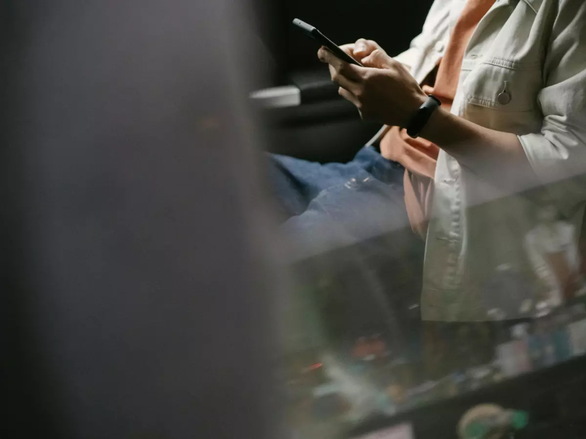 A person holding a phone with their right hand, using it in a dimly lit environment.