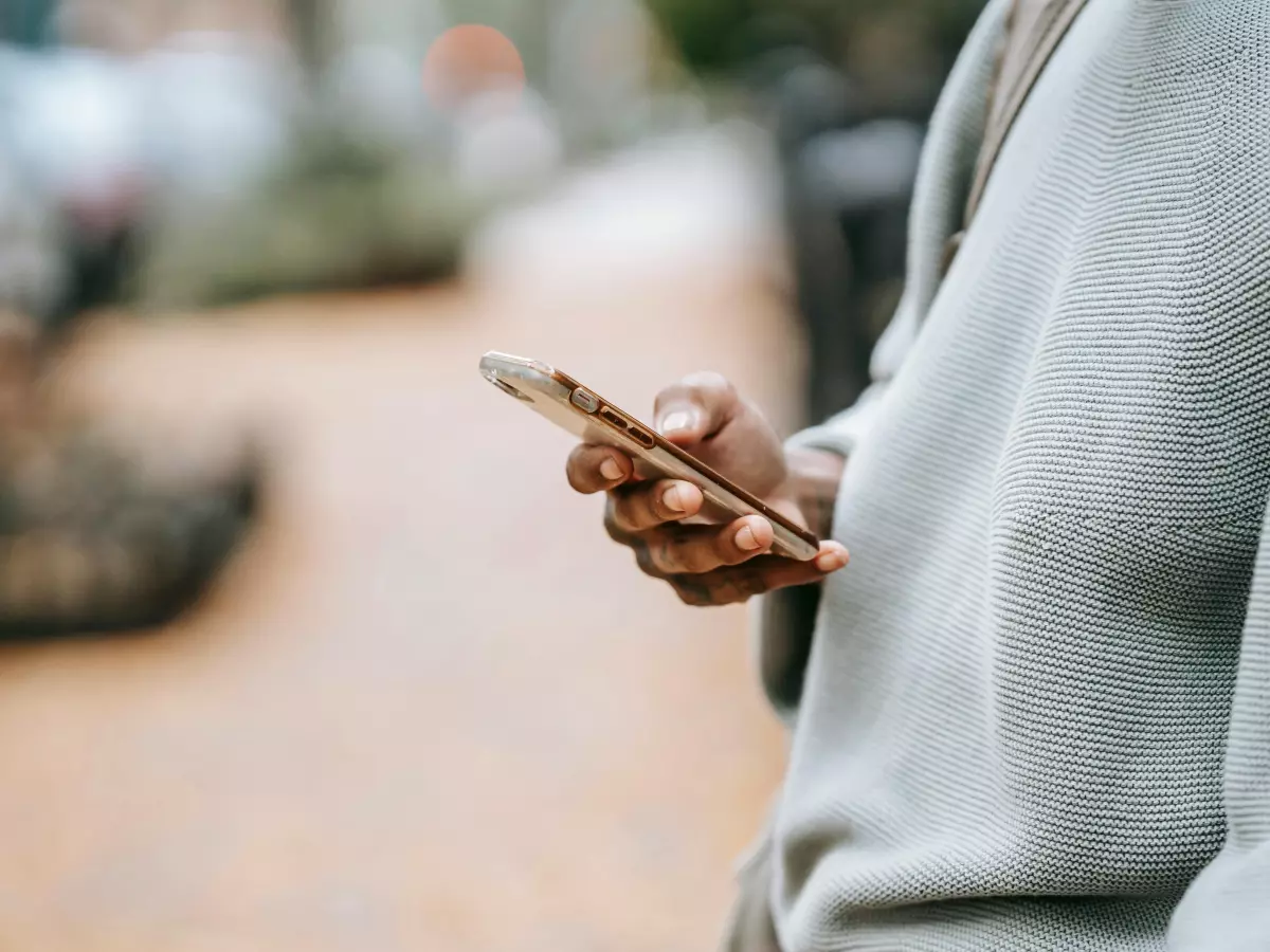 A person is holding a smartphone in their hand, the focus is on the hand and the phone.