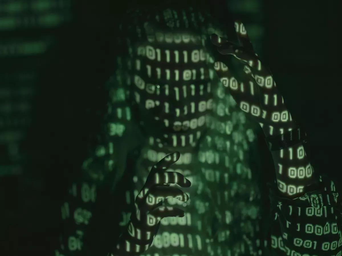 A close-up image of a hooded figure with binary code projected on them.