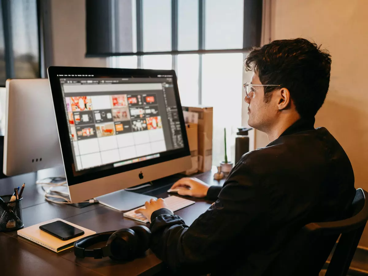 A man sits at a desk in front of a computer, typing on the keyboard.