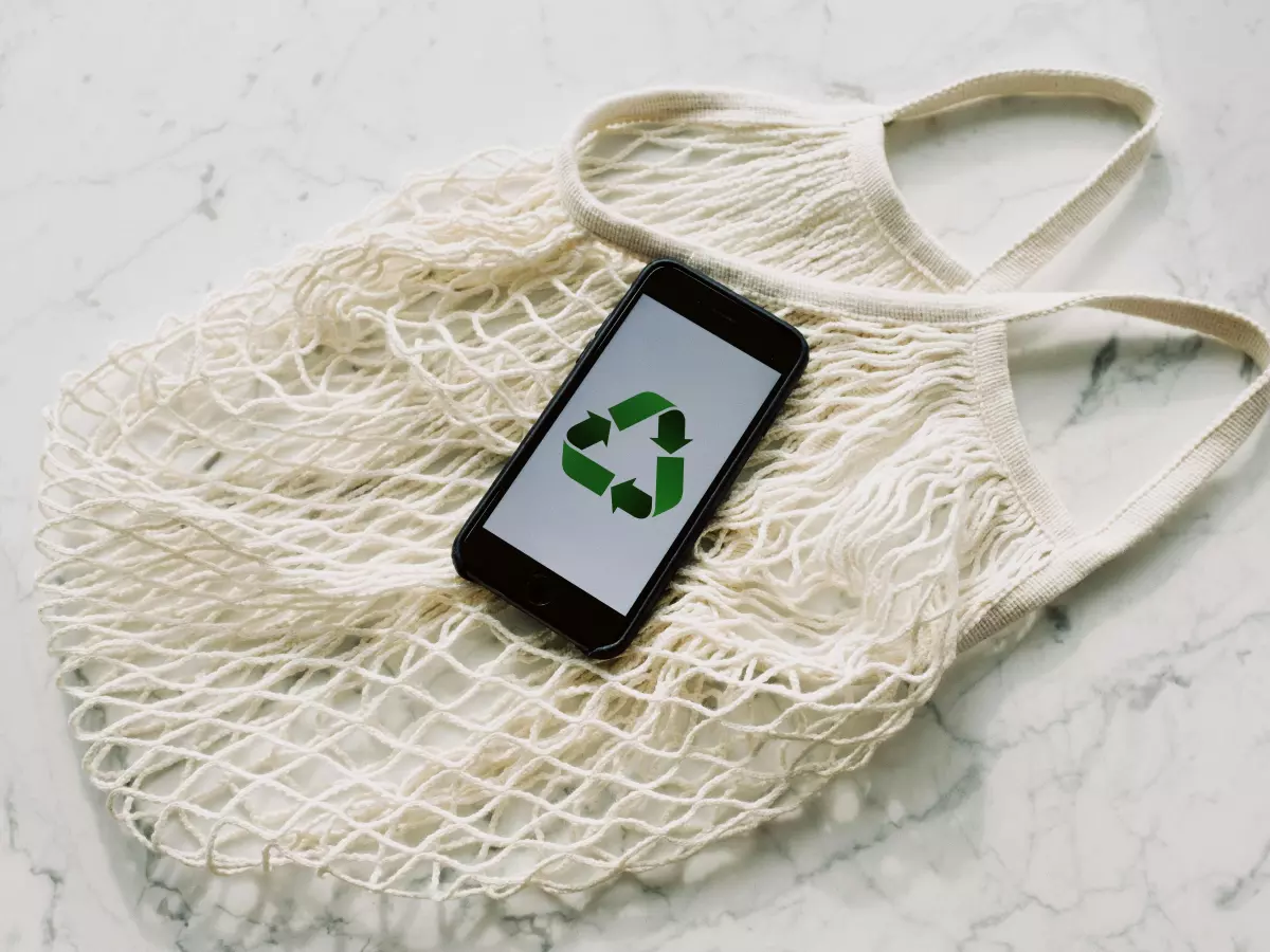 A close-up shot of a hand inserting a small, lime-green battery pack into a sleek, modern recycling slot. The overall image appears clean and futuristic, suggesting efficient and user-friendly EV battery recycling technologies.