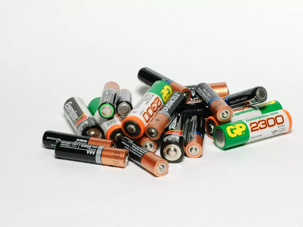 A pile of various types of batteries on a white background