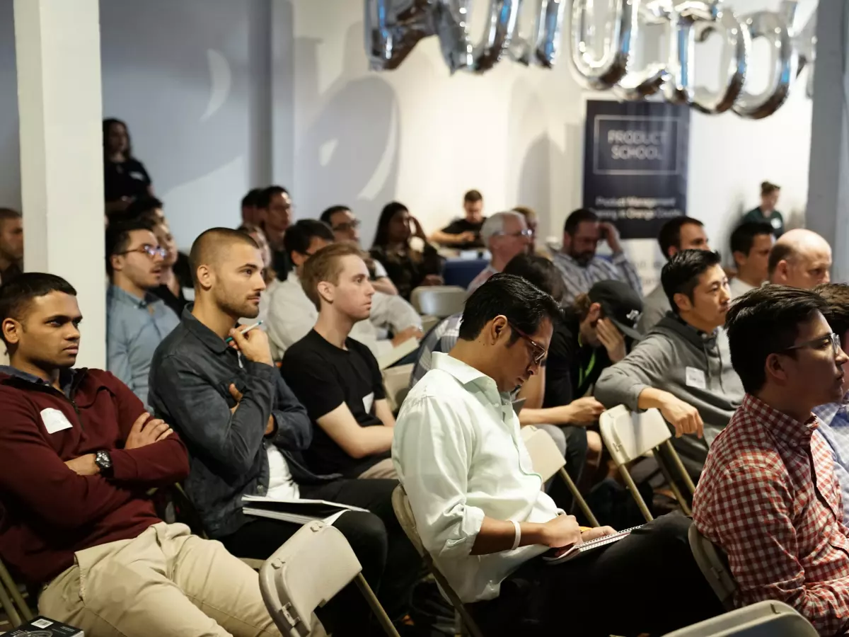 A large group of people are gathered in a conference room, listening to a speaker.