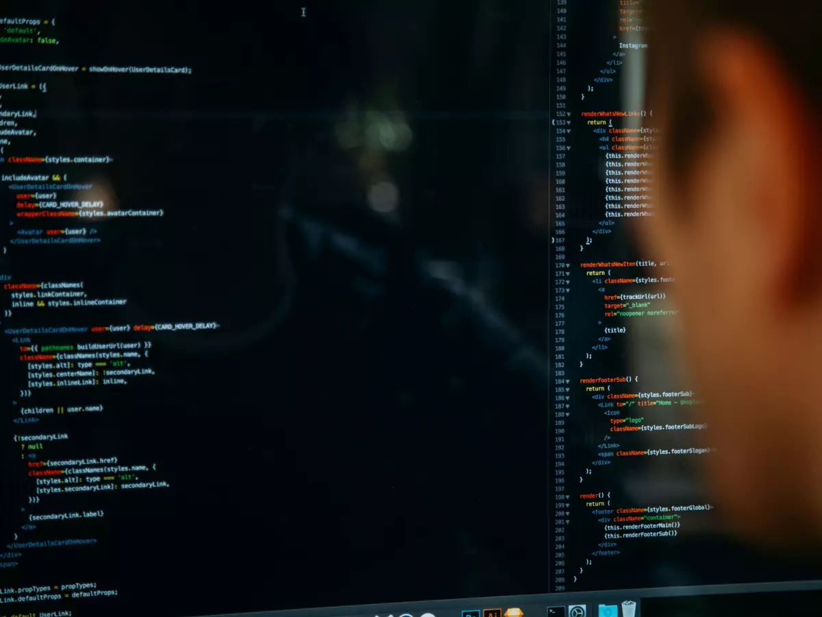 A person looking at a computer screen displaying code. The screen is filled with colorful lines of code, suggesting the complexity of software development.