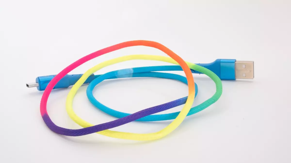 A rainbow-coloured cable is coiled up on a white surface.