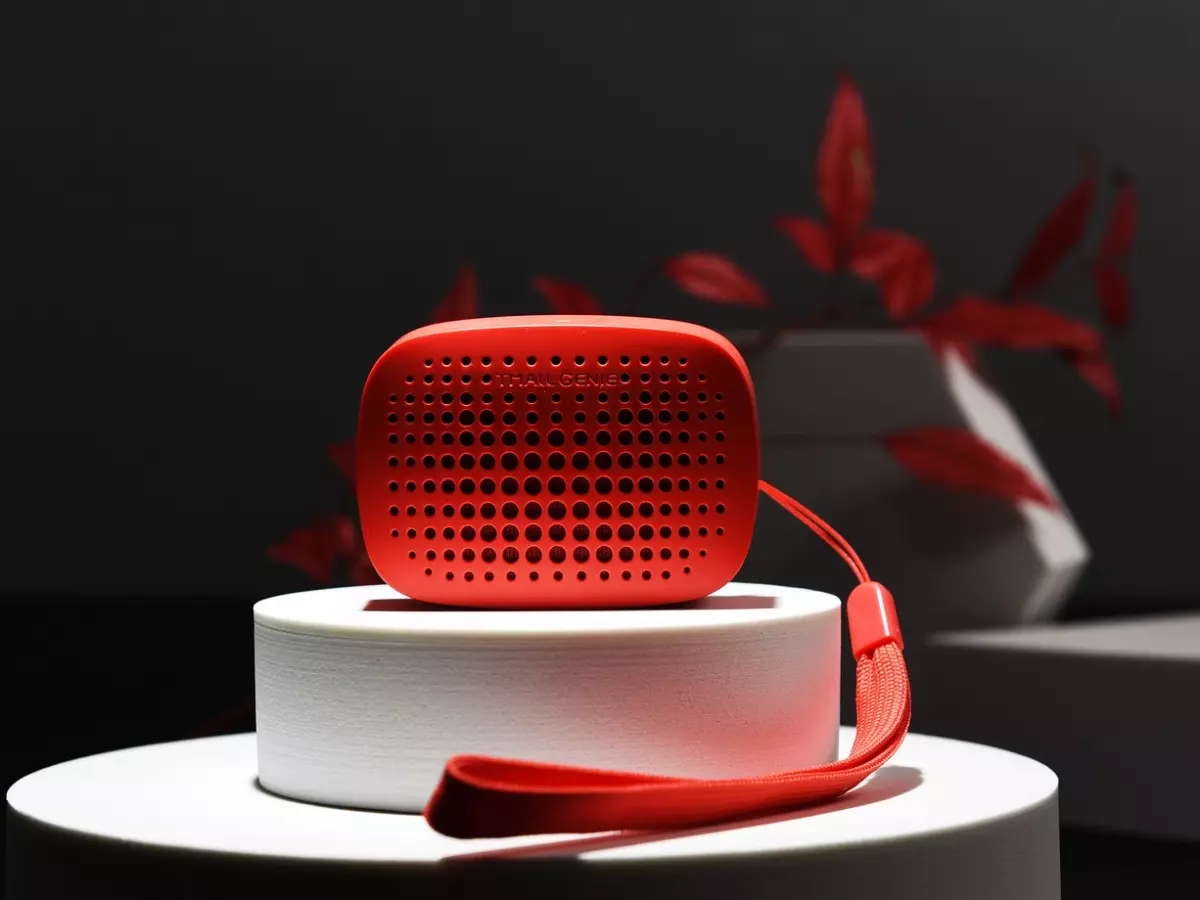 Close-up of a red smart speaker with a small strap on a white pedestal.