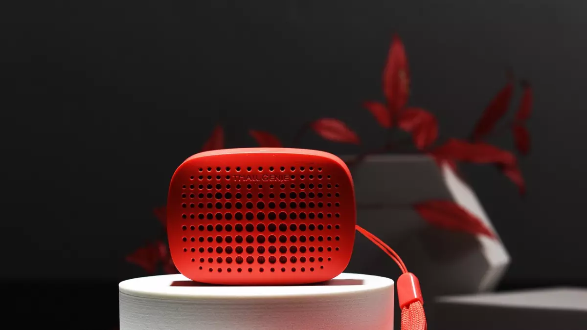 Close-up of a red smart speaker with a small strap on a white pedestal.