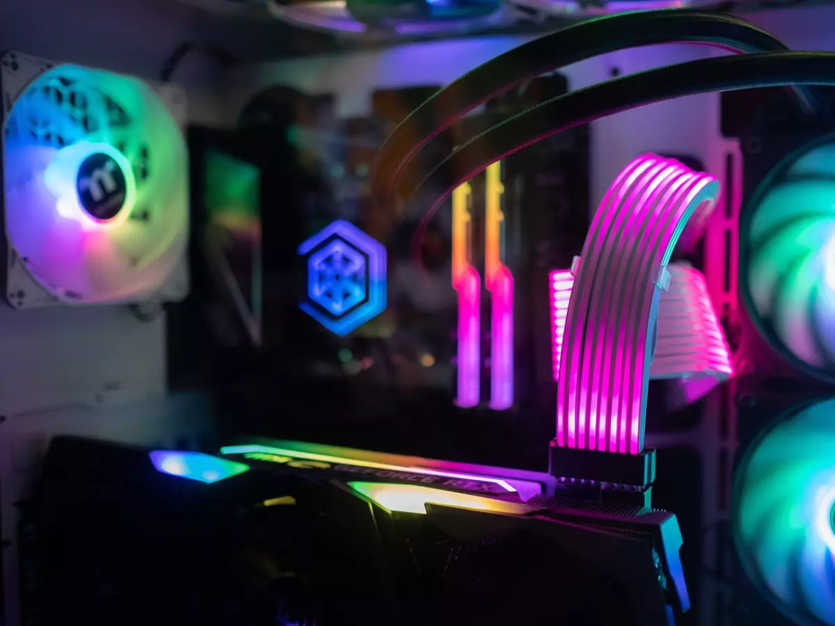 A close-up of a gaming PC setup with colorful RGB lighting and various components visible. The image focuses on the motherboard, CPU, graphics card, and fans.