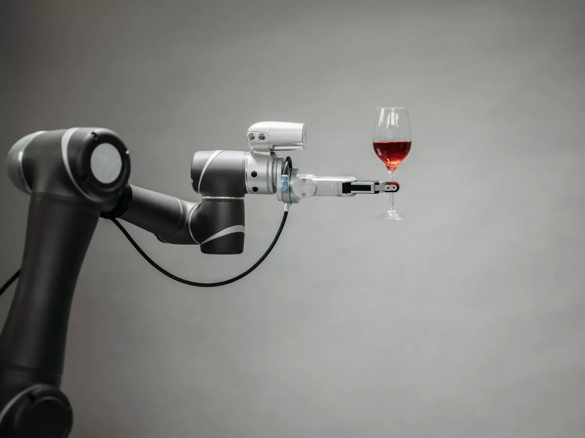 A robotic arm pours wine into a glass.