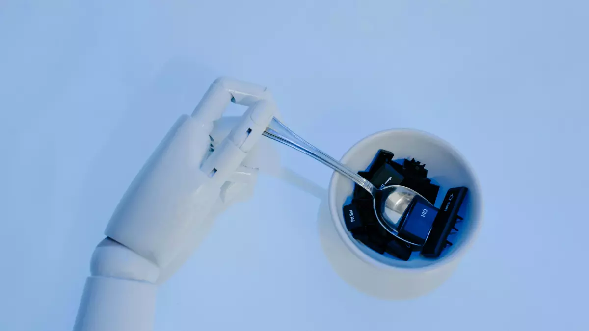 Close-up of a robotic hand, with delicate fingers, holding a small transparent sphere with blue and black internal components. The hand is white against a light blue background, emphasizing the mechanical precision.