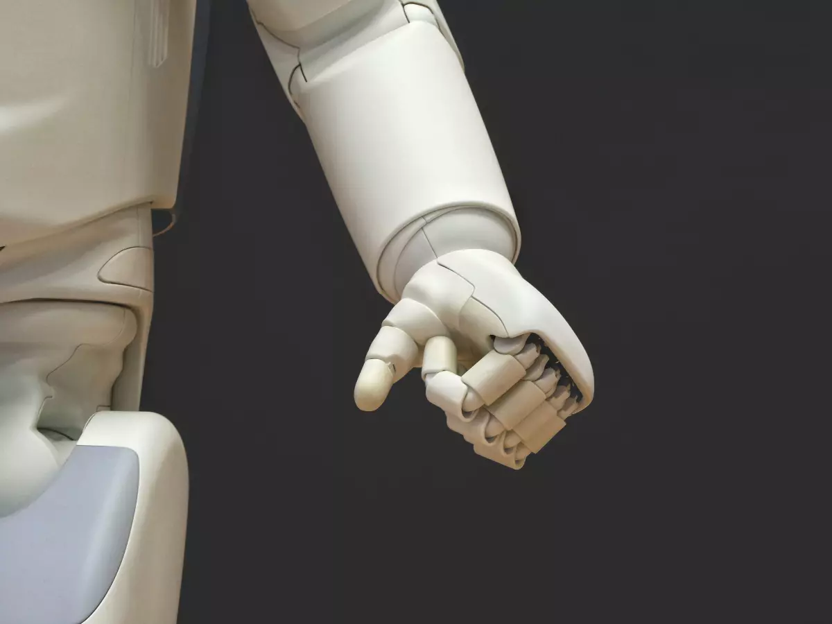 A close-up of a white robotic hand with articulated fingers, set against a black background.