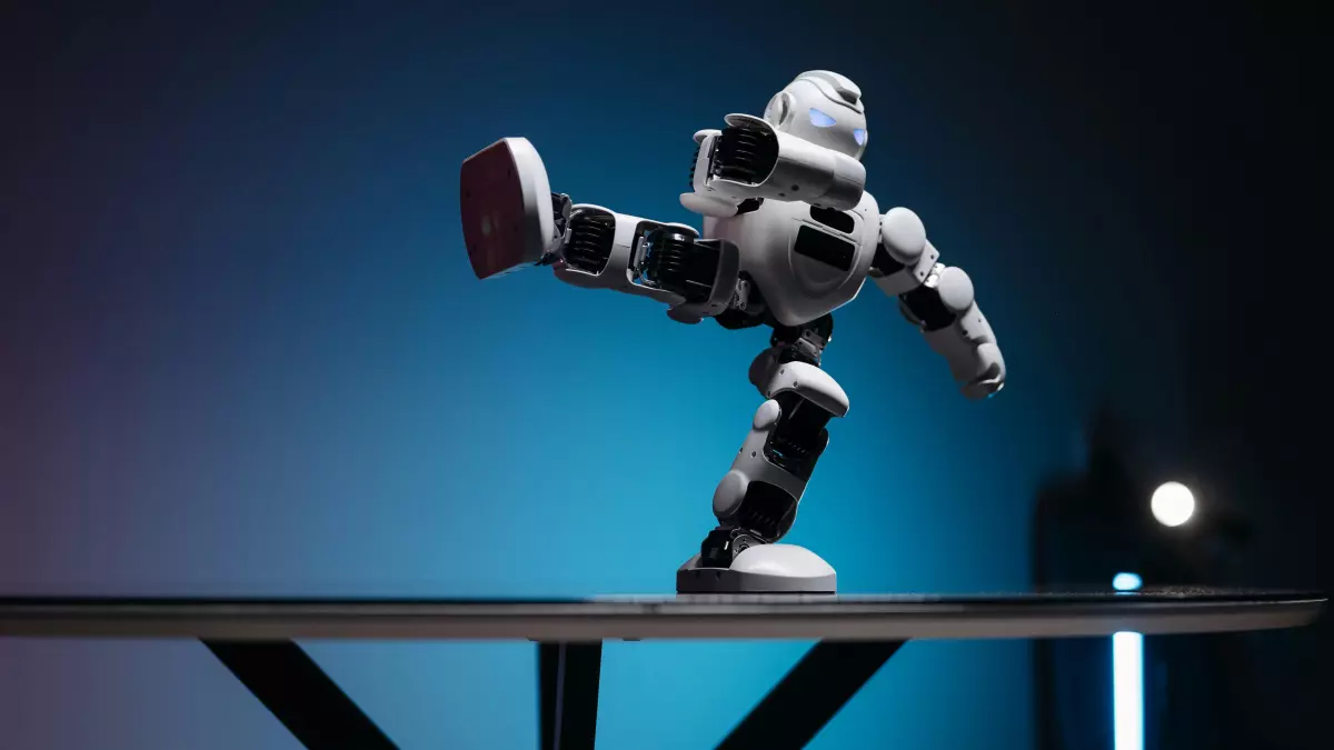 A white robot with black accents is shown kicking its leg while standing on a table. The background is blue, and the table is made of glass. The robot