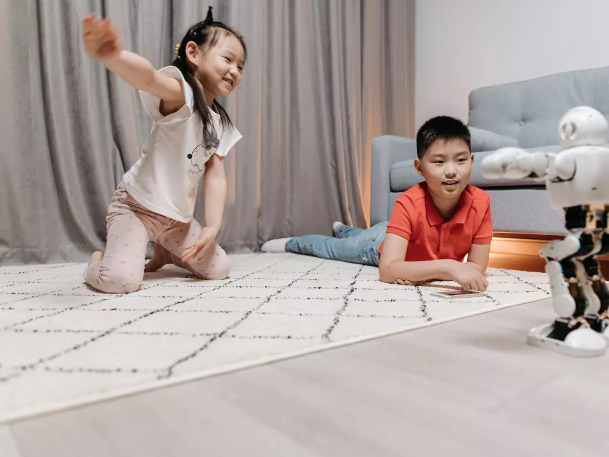 A humanoid robot interacts with two children in a living room.