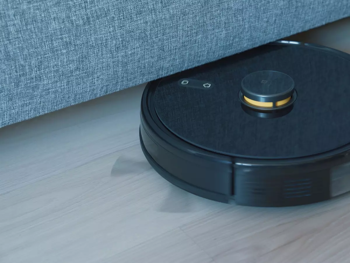 A Dreame robot vacuum cleaner is shown cleaning a wooden floor under a couch.