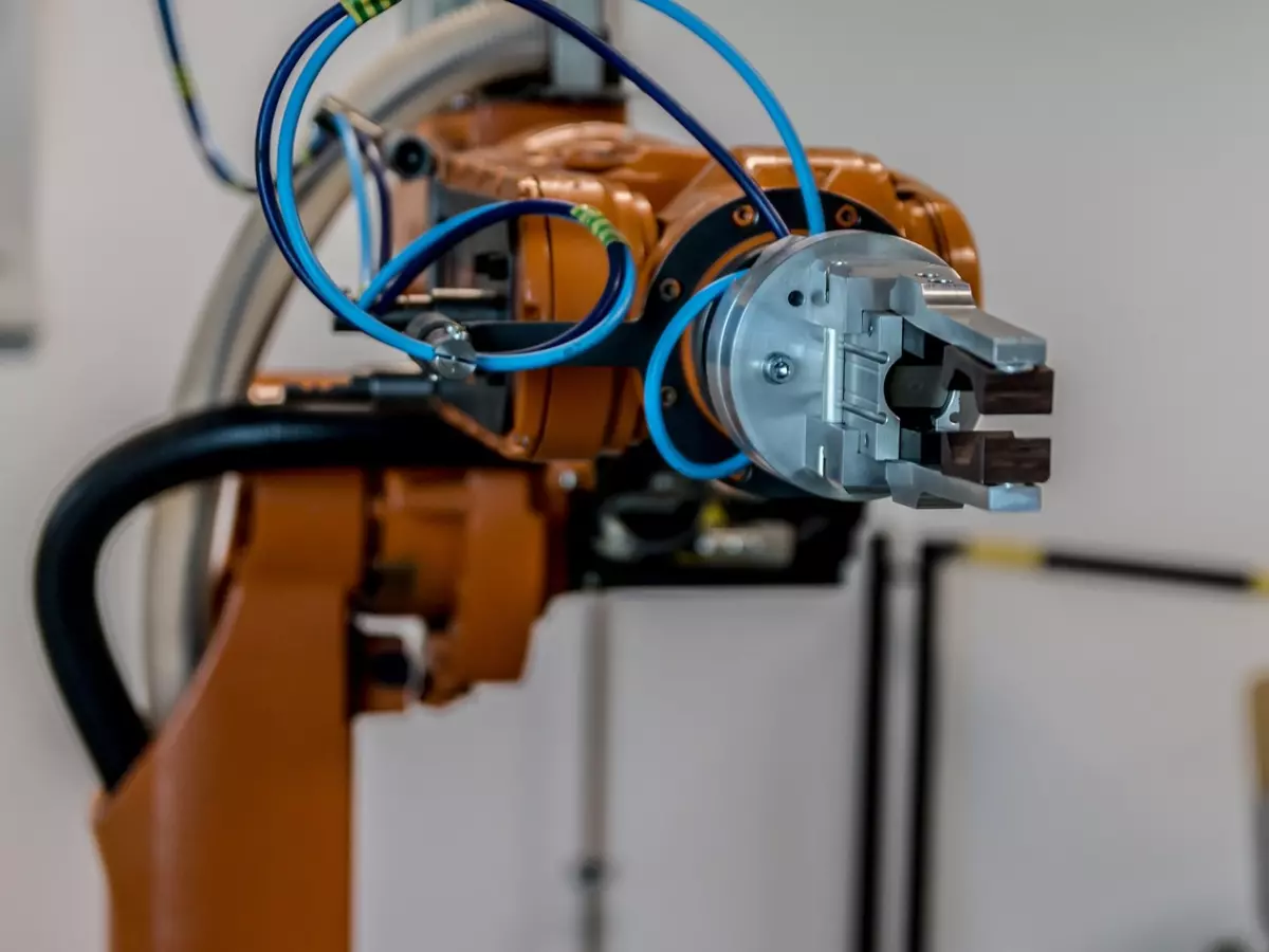 A close-up of an orange robotic arm with blue wires.