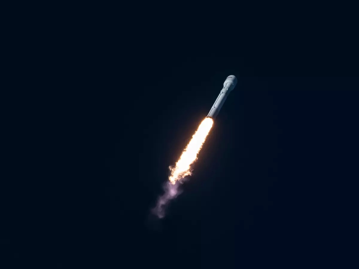 A rocket launches into the night sky, leaving a trail of fire and smoke behind it.