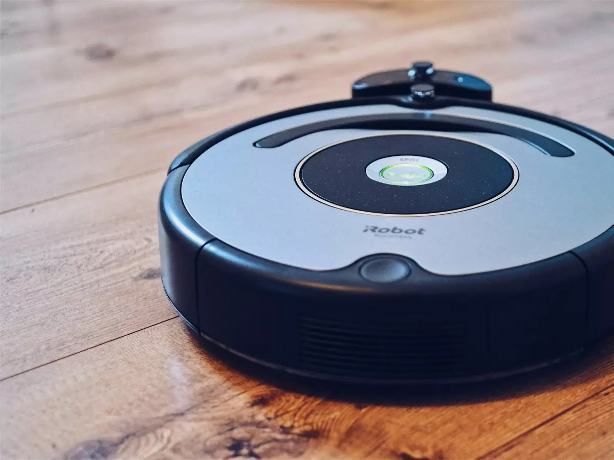 A robot vacuum cleaner on a wooden floor, with the charging station in the background.