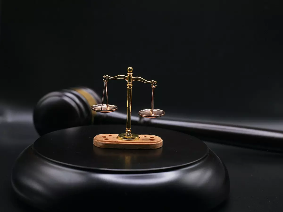 A gavel and a scale of justice on a wooden surface, black background.