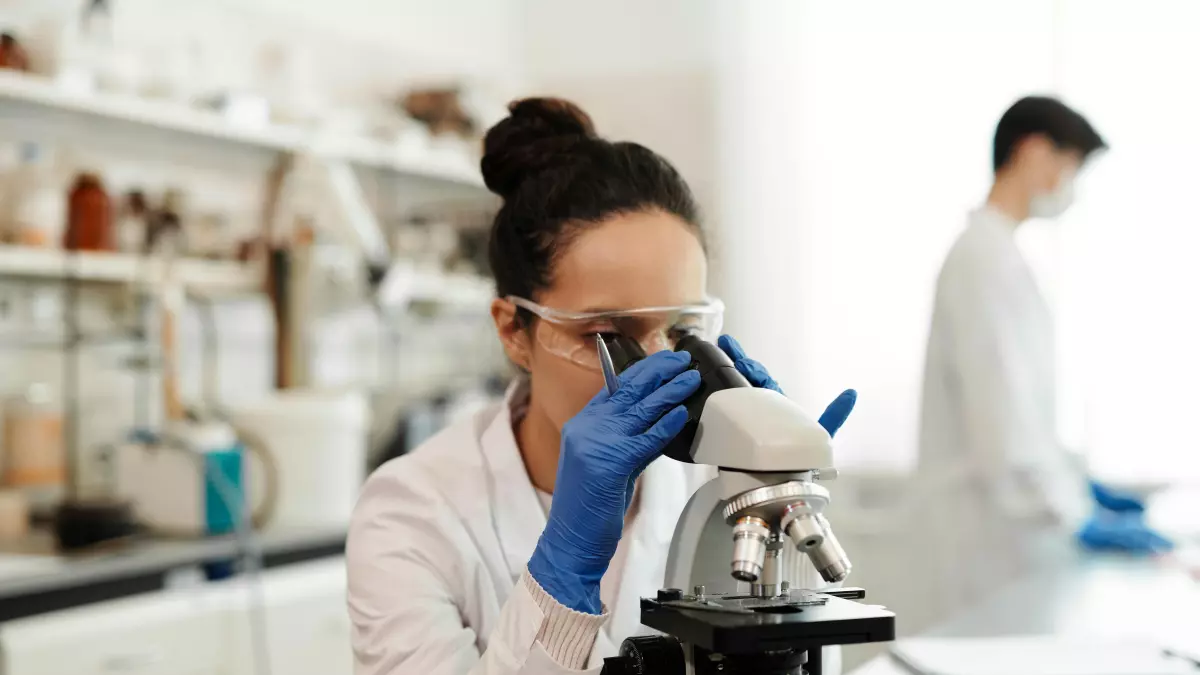 A scientist looking through a microscope in a lab.