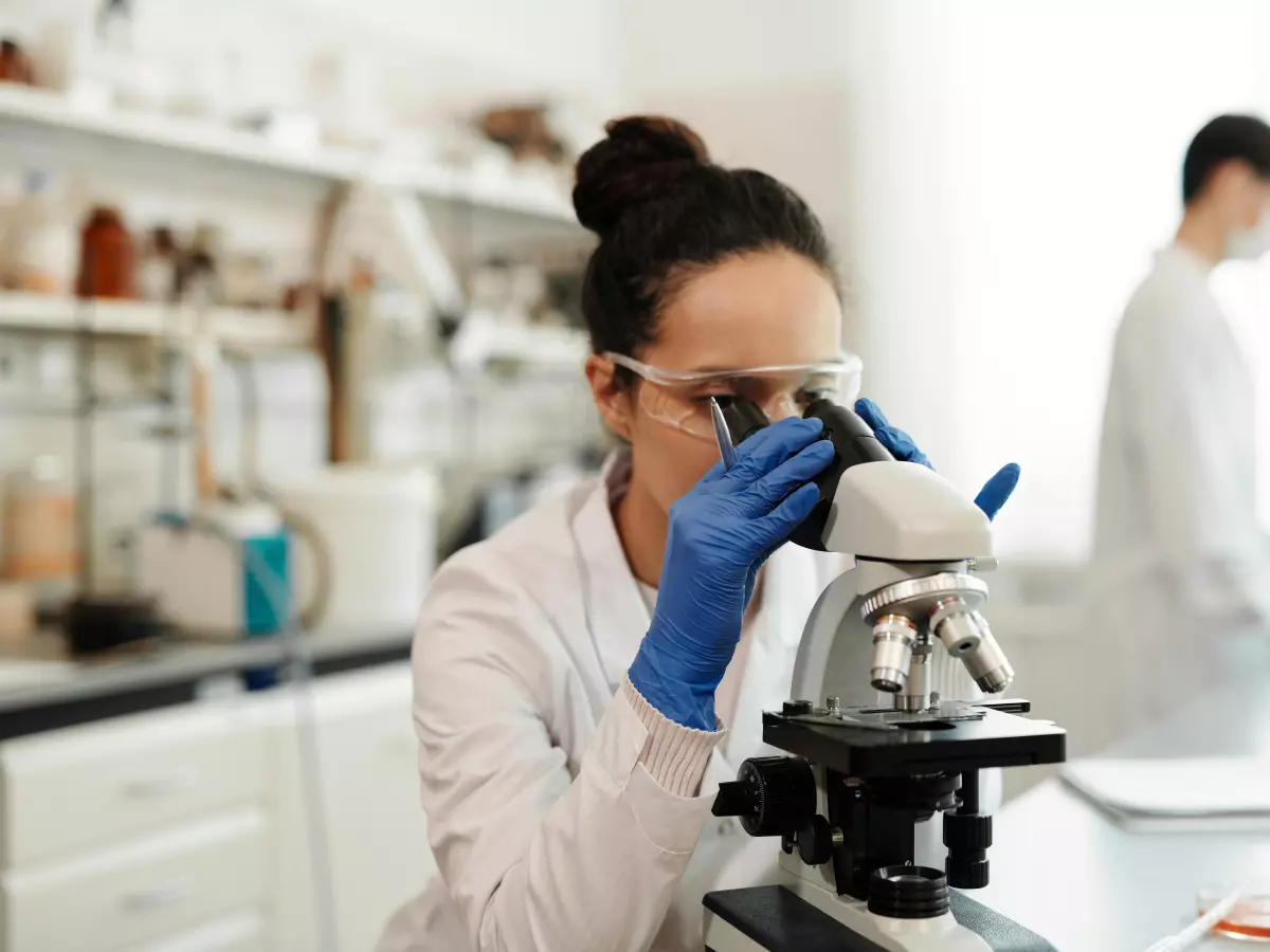 A scientist looking through a microscope in a lab.