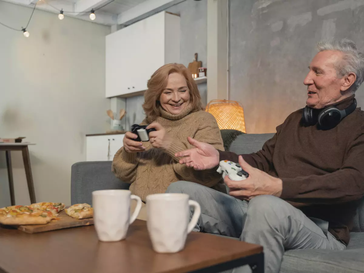 A couple is sitting on a sofa playing video games, they look excited and happy.