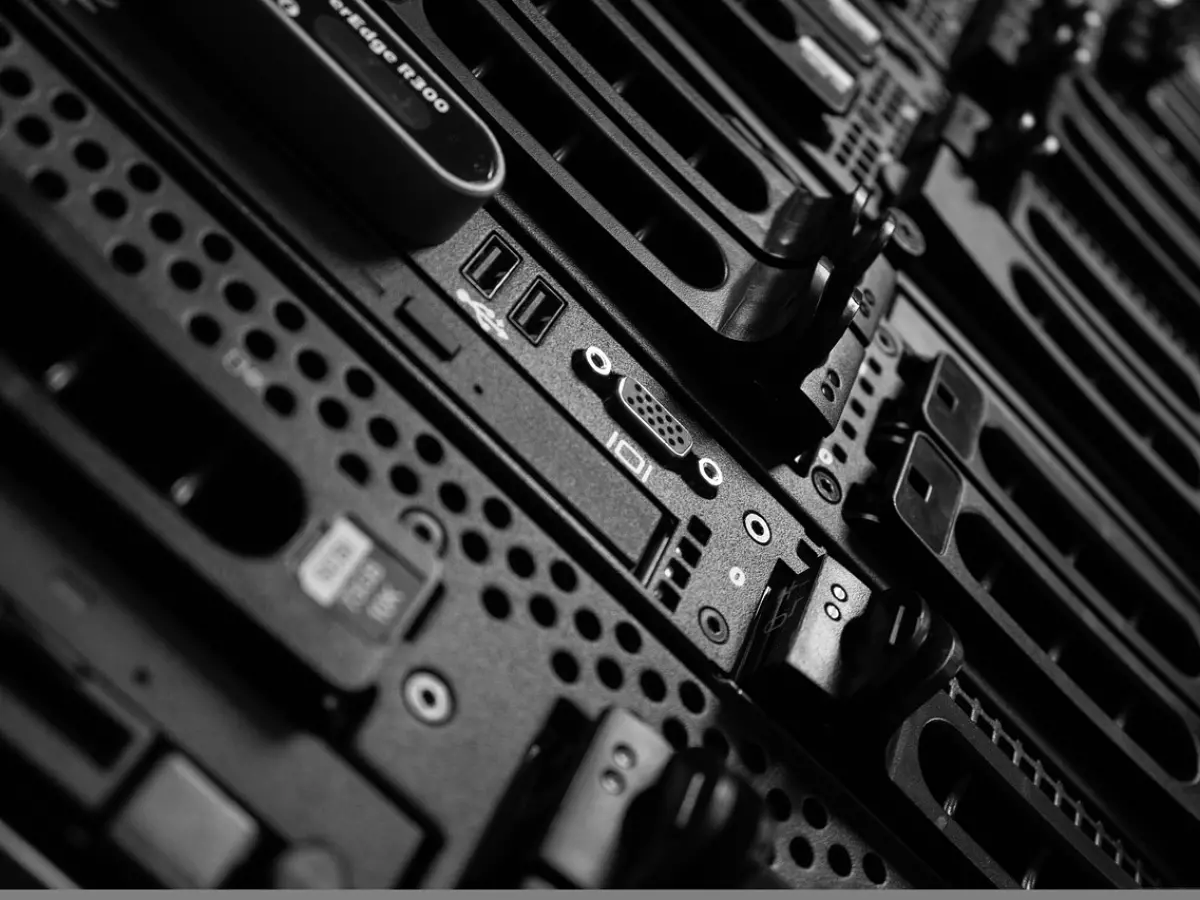 A close-up shot of the back of a server rack, showcasing the intricate network of connectors and cables. The black and grey color scheme emphasizes the technological complexity, while the angled perspective adds a sense of depth and intrigue.