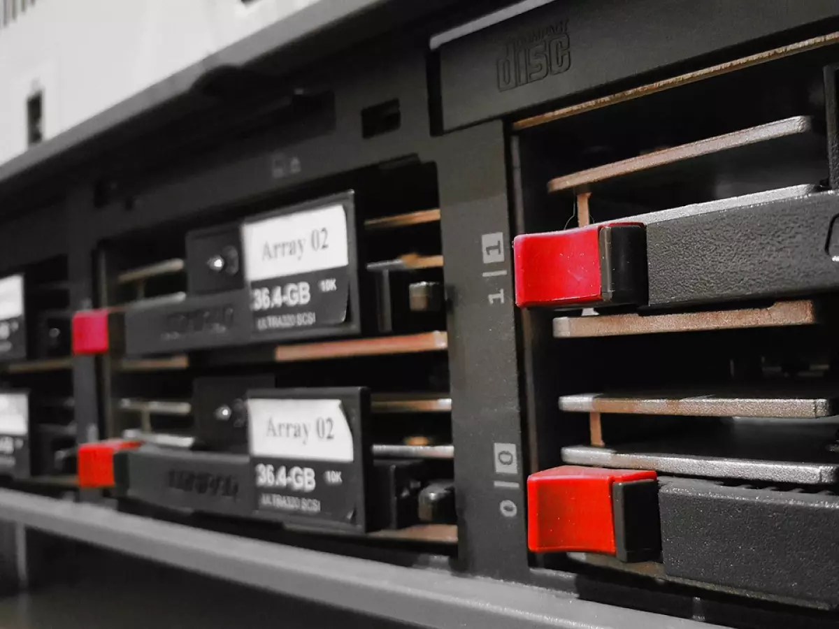 A close-up shot of a server rack with multiple hard drives and a Compaq logo. The image is taken from a low angle, making the server rack appear imposing.