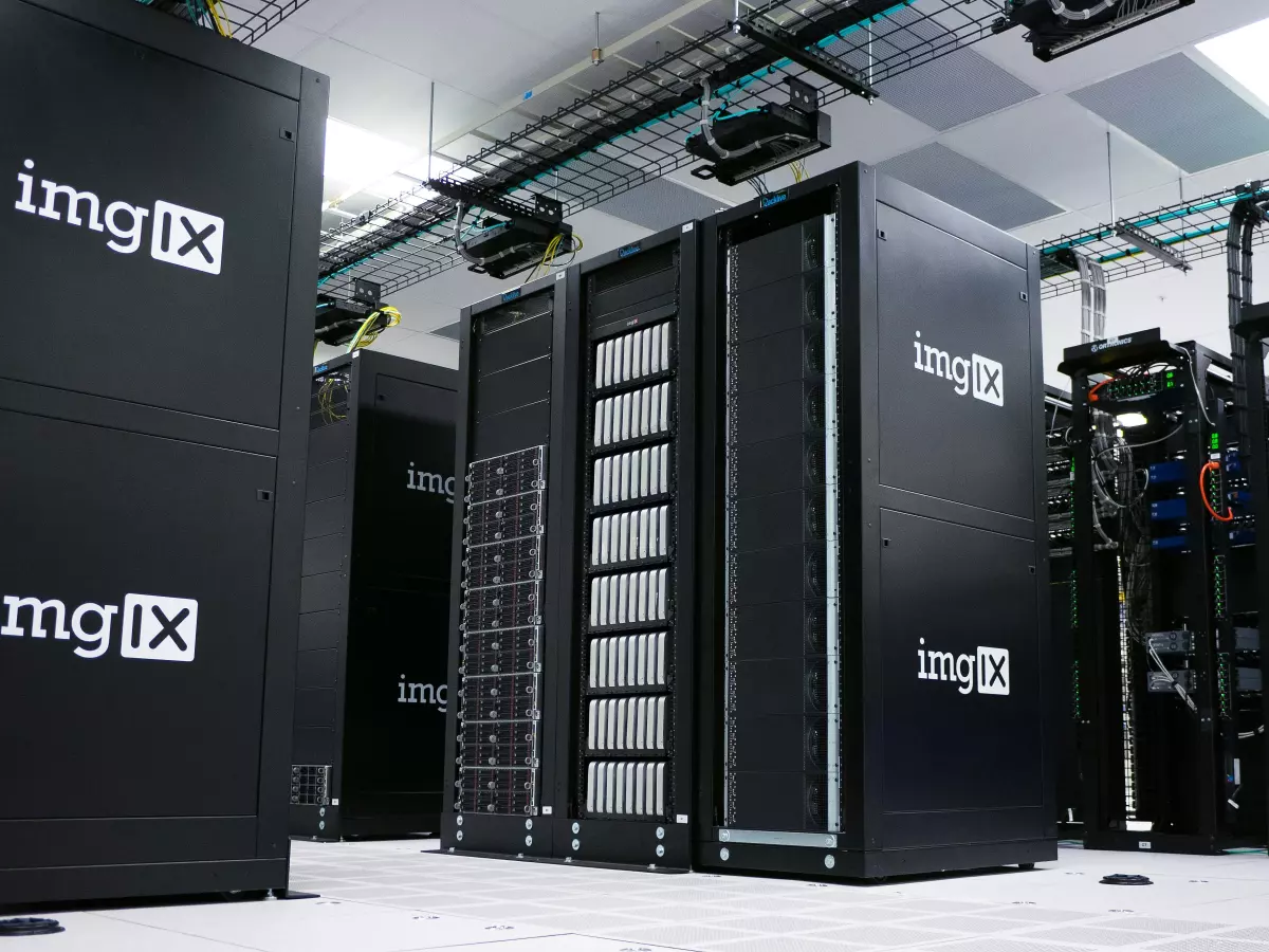 A server room with rows of black servers, all with the same logo. The servers are in a white room, with cables running overhead.