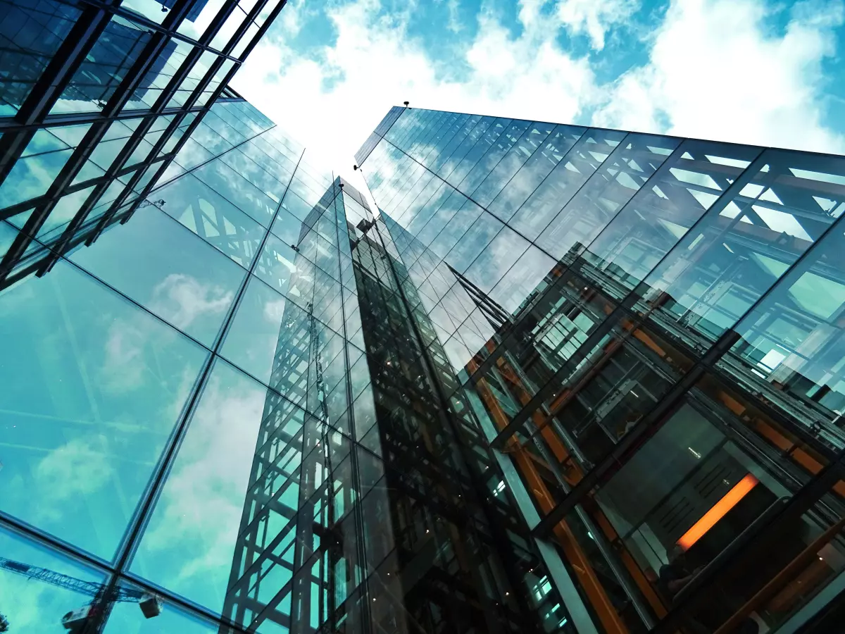 A low-angle shot of several skyscrapers, with the sky visible through their glass facades.