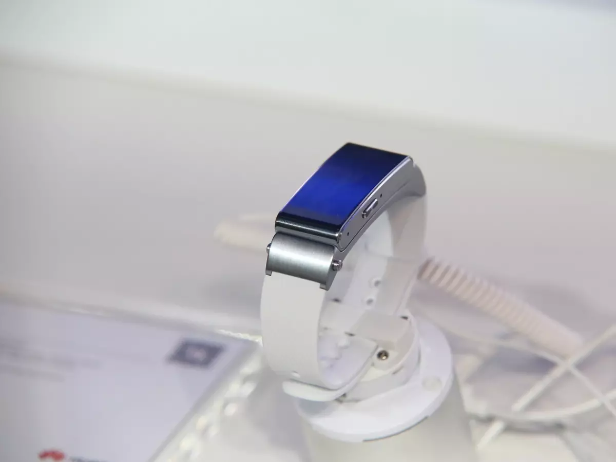 A white smartwatch on a stand, with a blue screen.