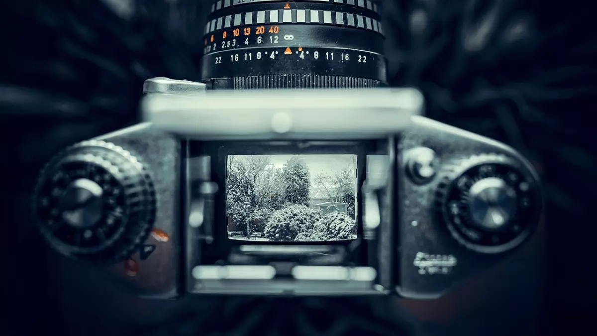 A close-up shot of a camera lens with a snowy landscape in the background.