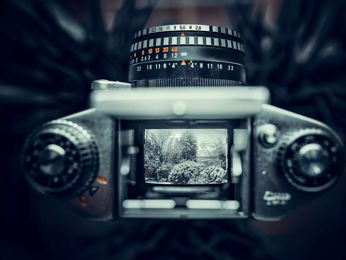 A close-up shot of a camera lens with a snowy landscape in the background.