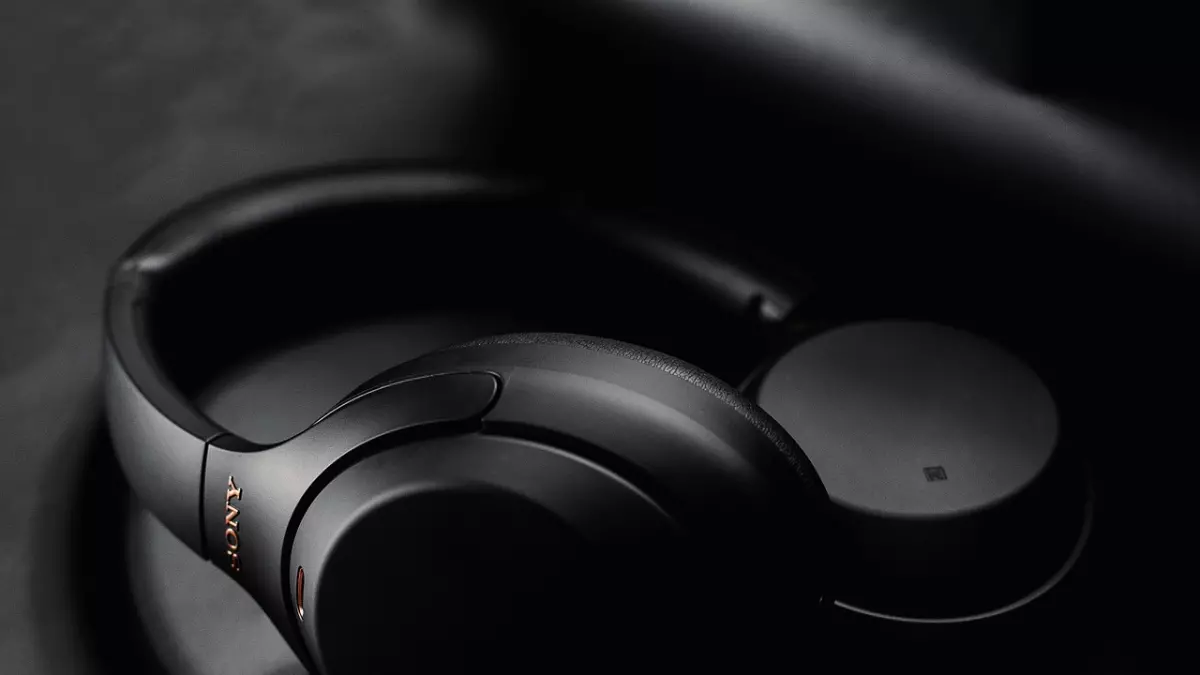 A close-up shot of a pair of black Sony noise-canceling headphones resting on a dark surface. The image is well-lit, highlighting the headphones