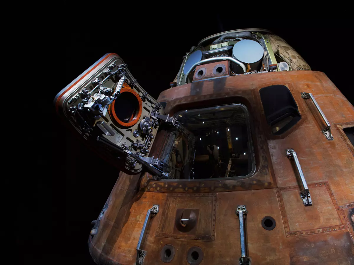 A close-up shot of the Starliner spacecraft with the hatch open, revealing the interior of the spacecraft. The spacecraft is lit by a bright light source from behind, which creates a dramatic effect. The image is taken from a low angle, which gives the spacecraft a sense of scale.