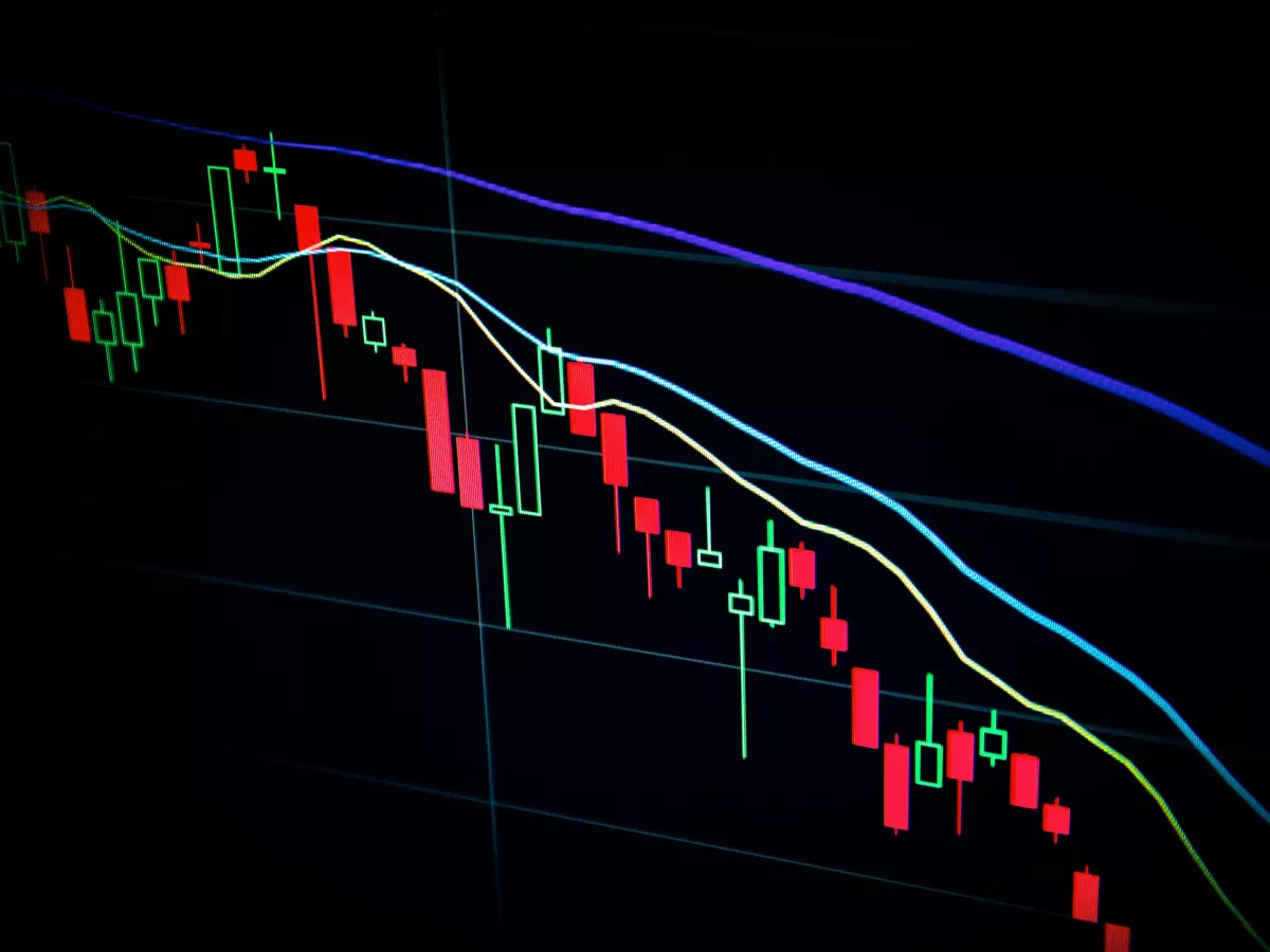 A close-up of a stock chart showing the price of a cryptocurrency, with red candlesticks representing downtrends.