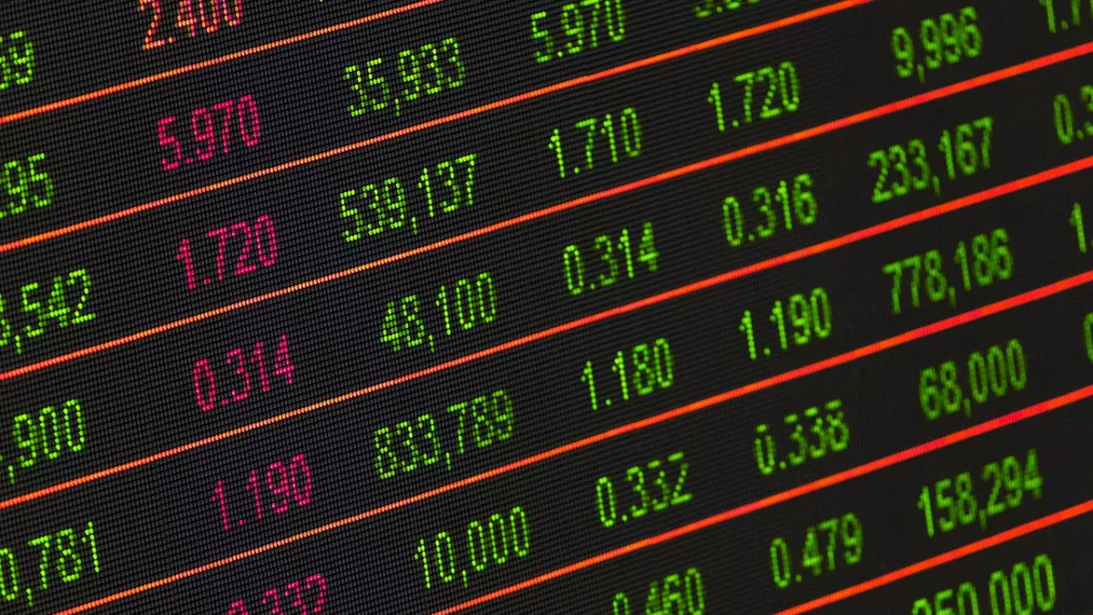 A close-up of a stock ticker with a black background, green and red numbers are displayed with red lines separating the rows of numbers.