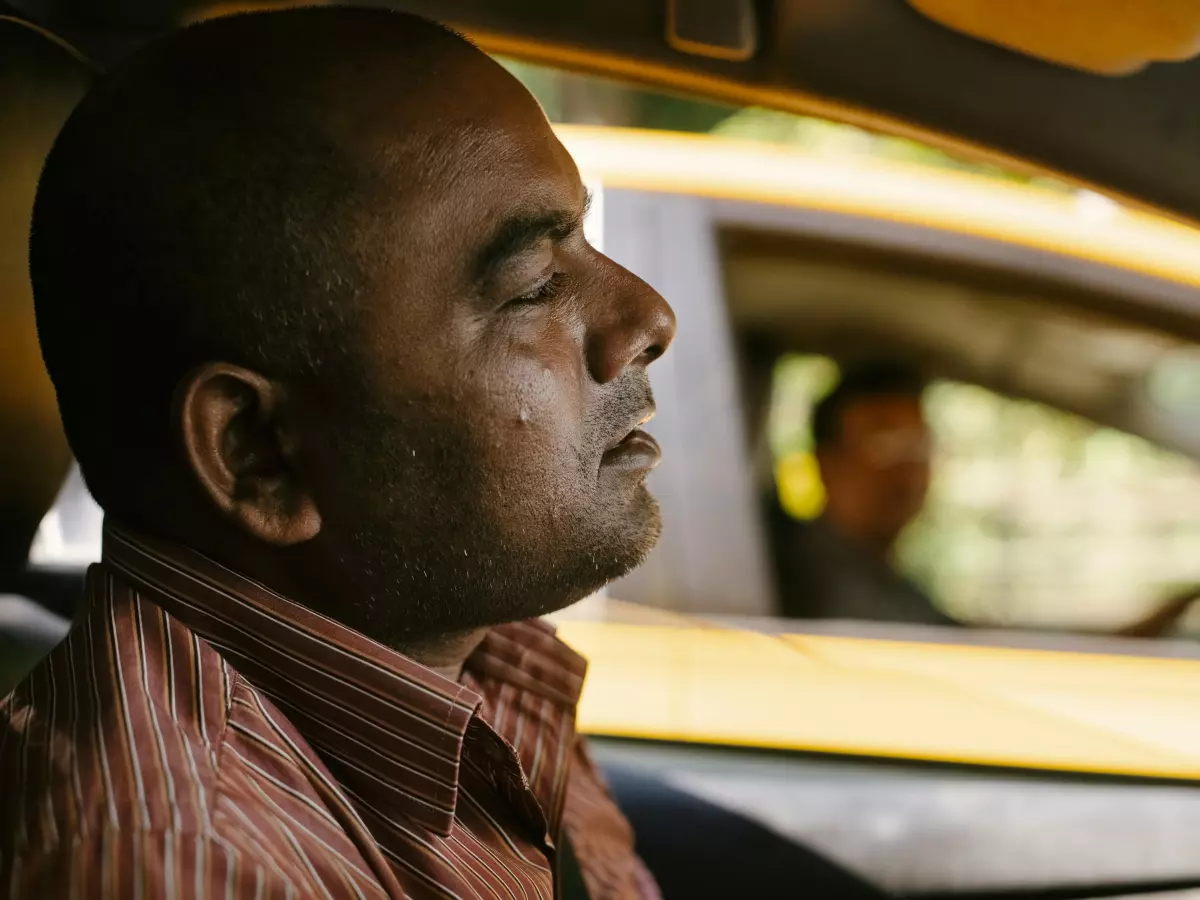 A person sitting in a taxi cab. The person's face is visible and they are looking out the window.