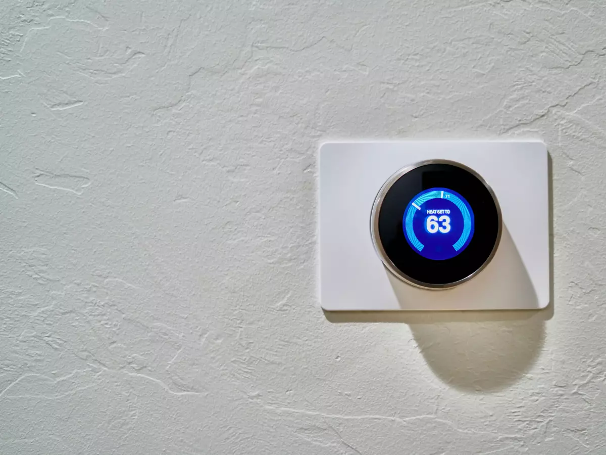 A close-up shot of a Google Nest Thermostat mounted on a wall, showcasing the digital display with temperature settings and the new brightness controls.