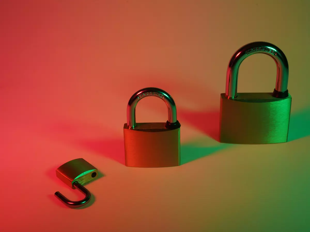 Three padlocks of different sizes are aligned. The padlock on the left is open, the middle one is closed, the right one is closed. The background is a gradient of green to red.