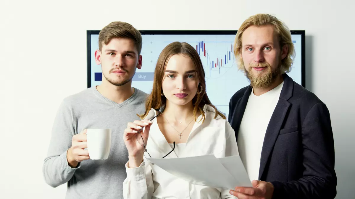 A group of people are standing in front of a large screen with data on it. They are looking at the screen intently. 