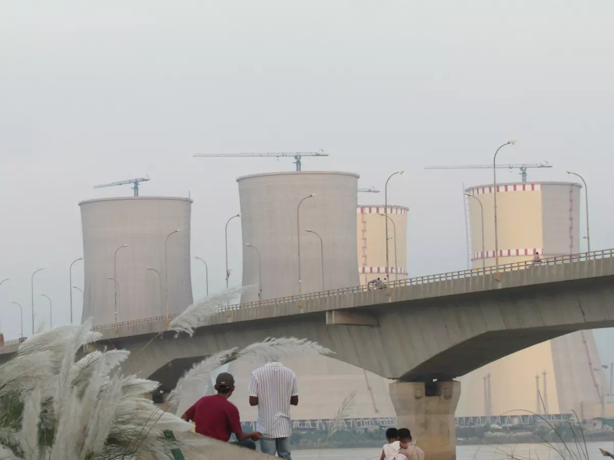 A view of a nuclear power plant with cooling towers, taken from a bridge.