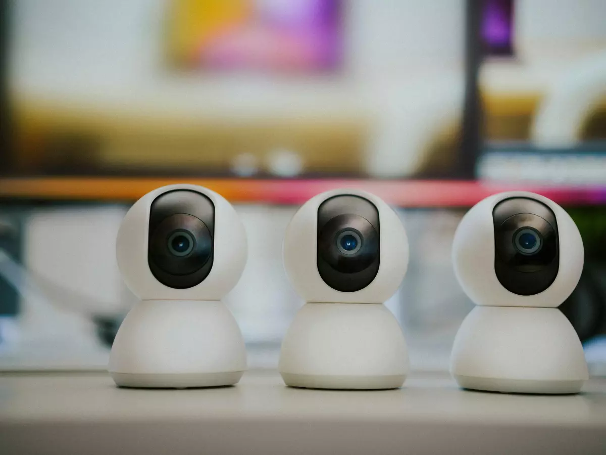 Three white smart security cameras are placed in a row on a desk.