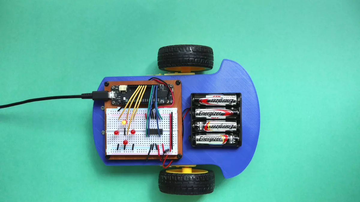 A small robot with a breadboard, batteries, and wires. 