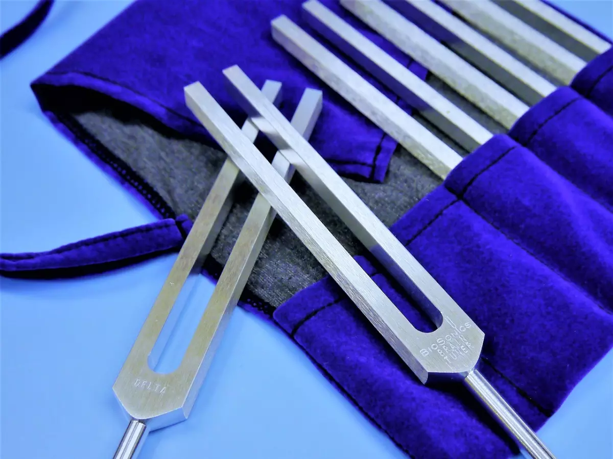 A set of tuning forks in a purple velvet pouch, on a blue background.