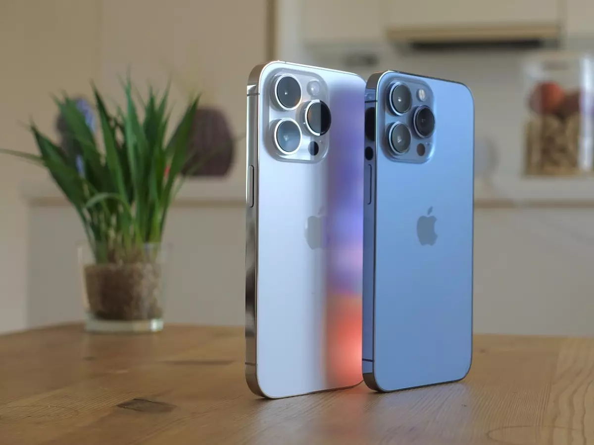 Two iPhones side by side on a wooden table.