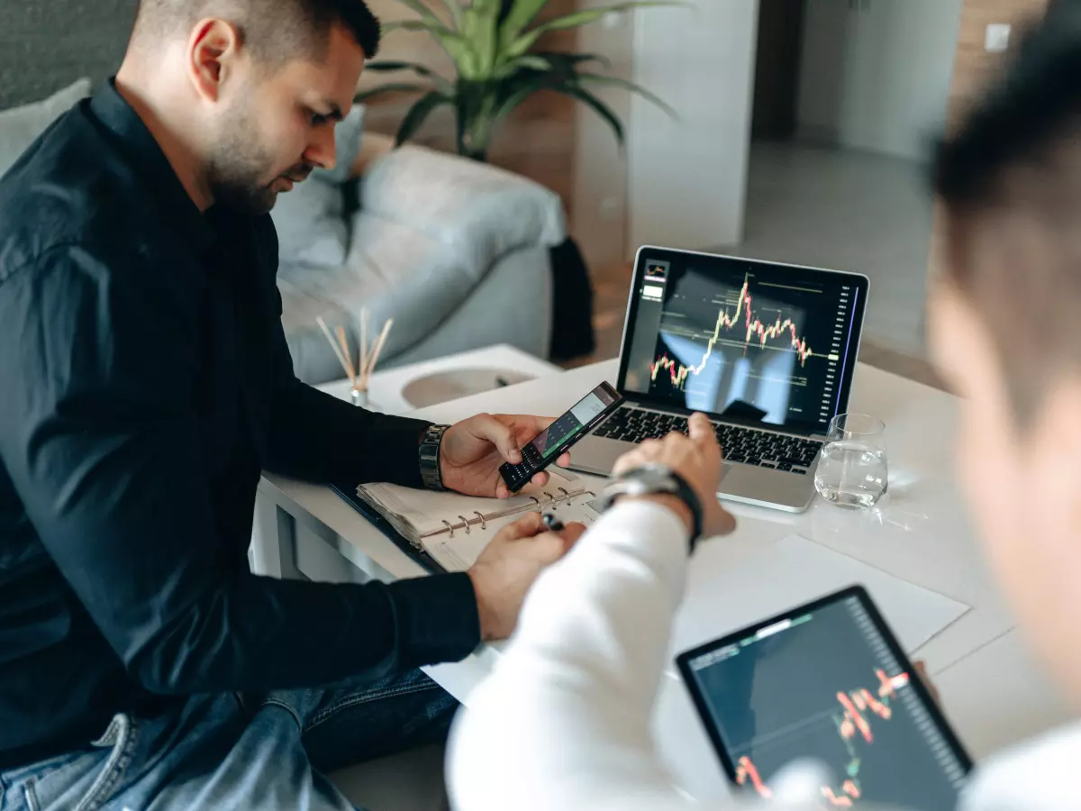 Two men are working on their laptops in an office setting.